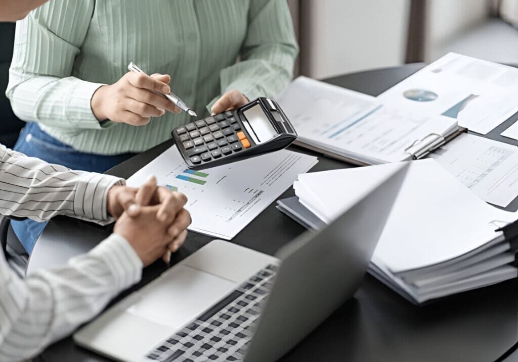 Two people are sitting at a table with papers and calculators.